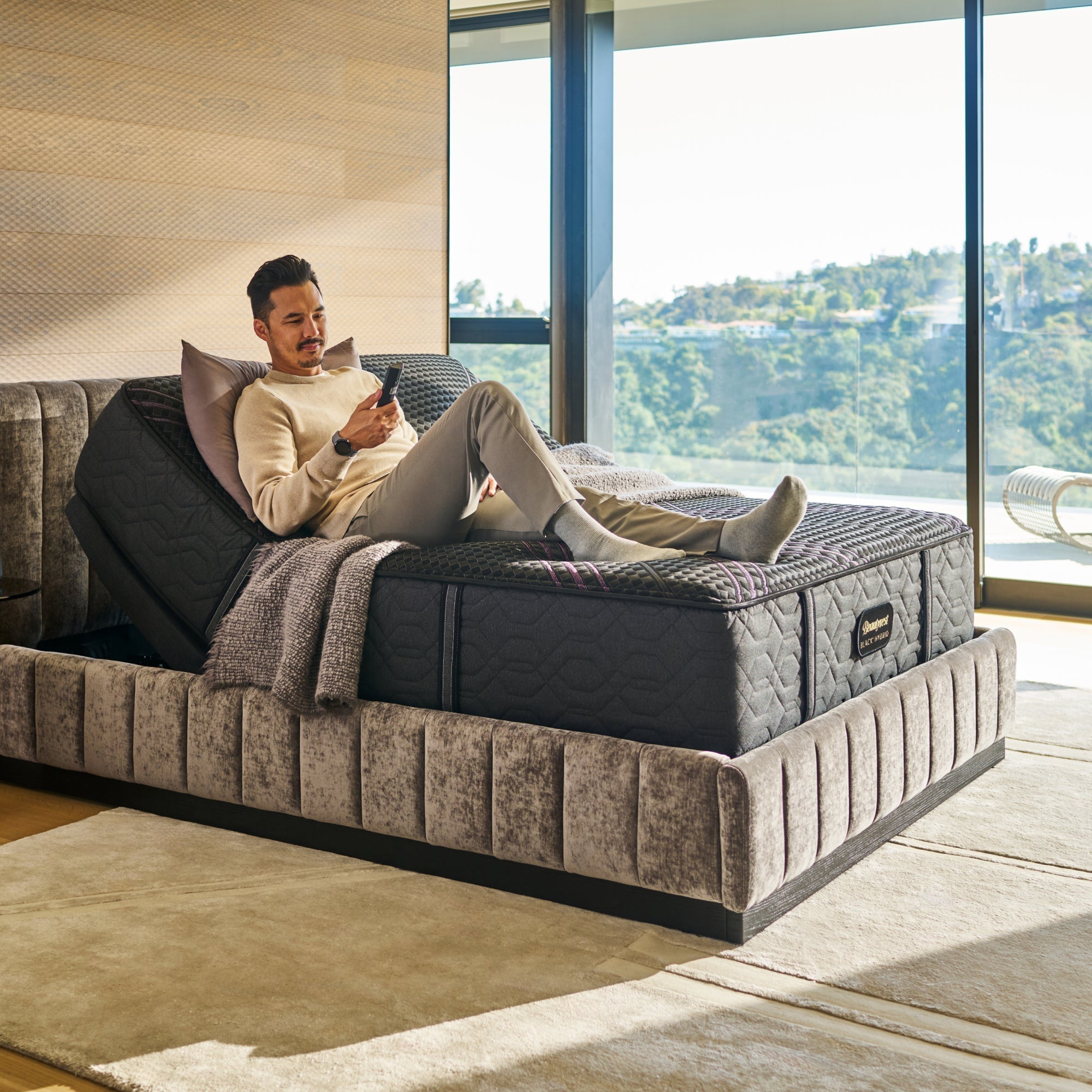 Man sitting on BeautyRest Firm Hybrid mattress sitting on an adjustable base || series: Series Two || feel: Firm