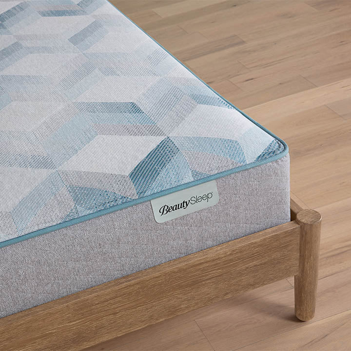 Gray mattress with geometric pattern on a wooden bed frame, featuring the BeautySleep brand.